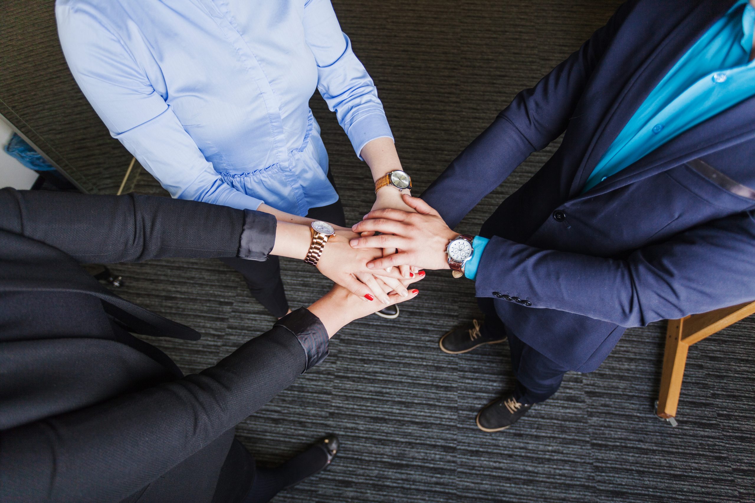 people-standing-office-holding-hands-together