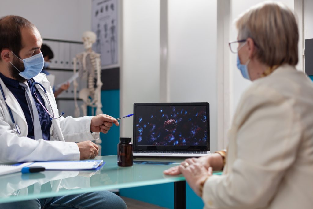 Specialist and patient looking at virus presentation on laptop